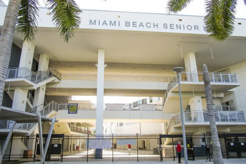 L'edificio a più piani della Miami Beach Senior High School è circondato da palme e delimitato da una recinzione.