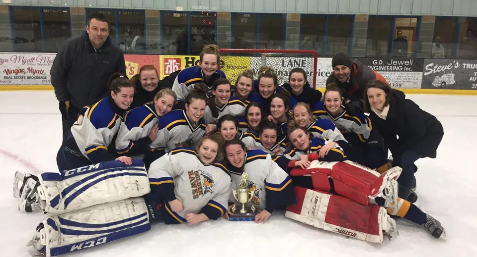 Studentesse della Napanee District Secondary School festeggiano la loro vittoria sul ghiaccio con un trofeo.