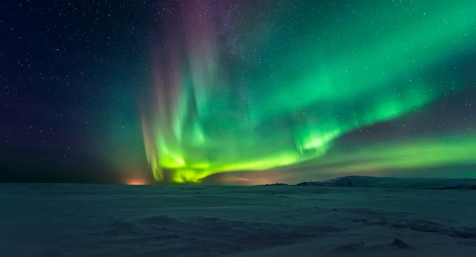 Sopra un paesaggio innevato, l'aurora boreale risplende sul terreno della Fort St. James Secondary.