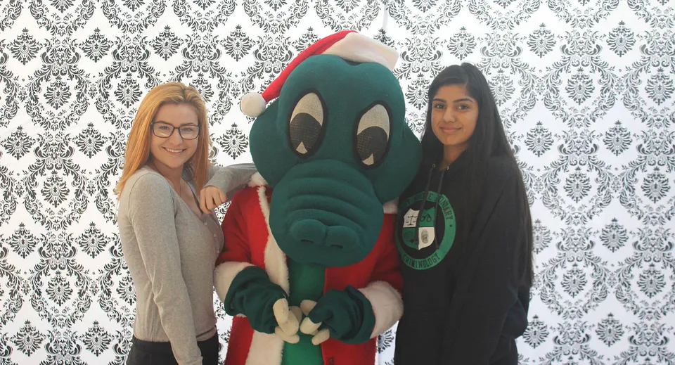 Due studentesse posano con un grande personaggio dei fumetti verde davanti a una carta da parati a motivi alla Walnut Grove Secondary School.