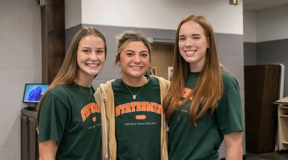 Tre studentesse sorridenti in piedi insieme in un corridoio del campus dell'Illinois Eastern Community Colleges.