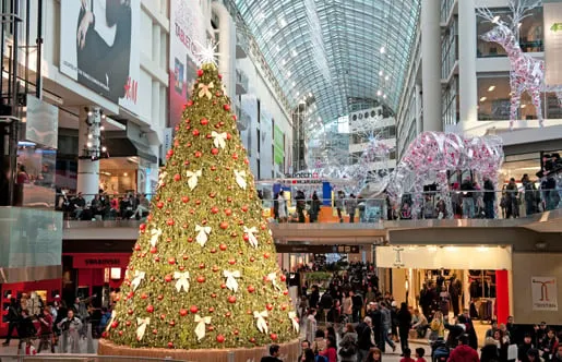 Gran árbol de Navidad iluminado en el centro de un centro comercial repleto de gente