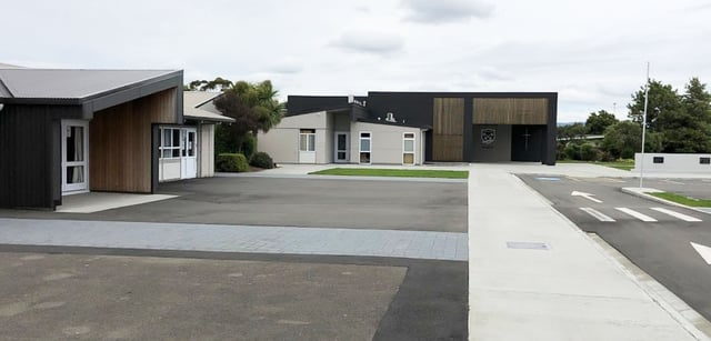 L'edificio moderno del St. Peter's College con vialetto pavimentato e aree verdi curate sotto un cielo nuvoloso.
