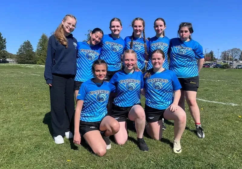Equipo femenino de rugby con camiseta azul de los Panthers posando en el campo de hierba