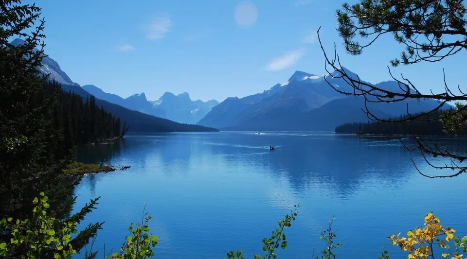 Un tranquillo lago alpino con una piccola barca, circondato da montagne e vegetazione, vicino alla Maxwell Heights Secondary School.