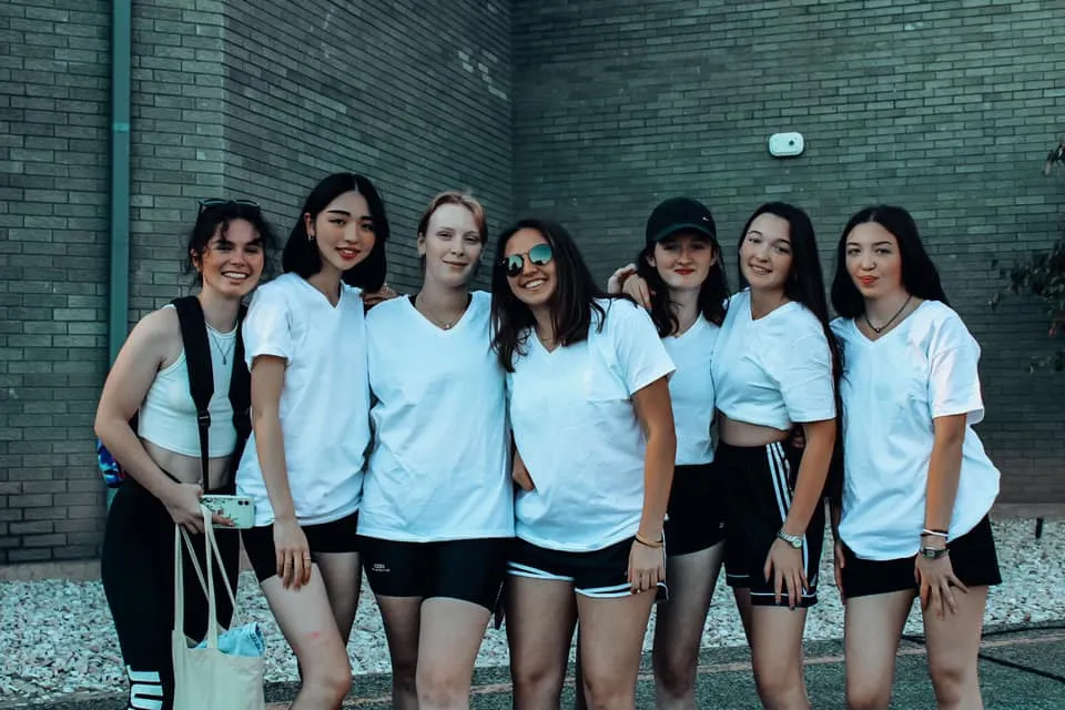 Un gruppo di studentesse della Layton Christian Academy posa per una foto di gruppo davanti a un muro di mattoni.