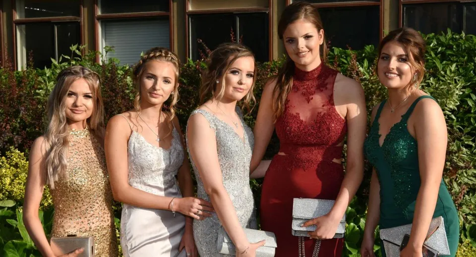 Cinque studentesse della St. Mary's Holy Faith Killester posano davanti a un edificio con piante verdi.