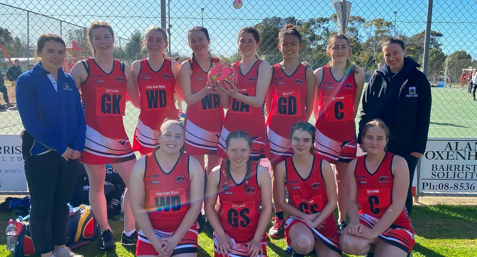 Un gruppo di giovani atlete con divise rosse e bianche sul campo sportivo della Kangaroo Island Community Education.