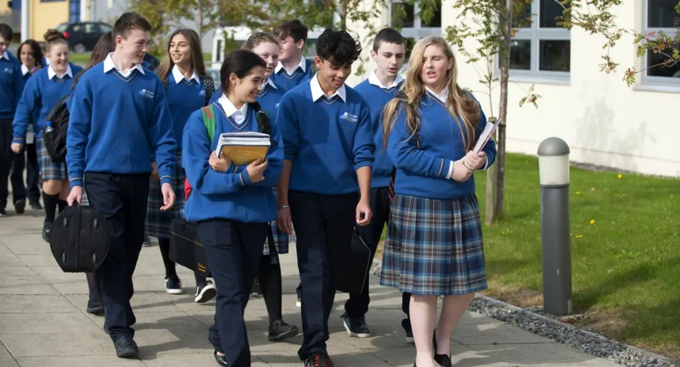 Studenti del Tyndall College con divise scolastiche blu camminano insieme nel campus della scuola.
