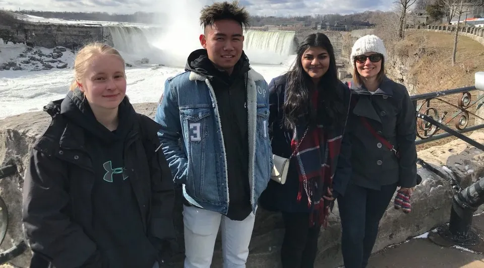Studenti della Heritage Christian Academy in abiti invernali posano davanti a una cascata innevata.
