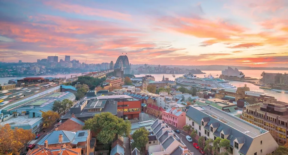 Un vivace paesaggio urbano con edifici colorati e un porto animato al tramonto, non situato direttamente presso la The Hills Grammar School.