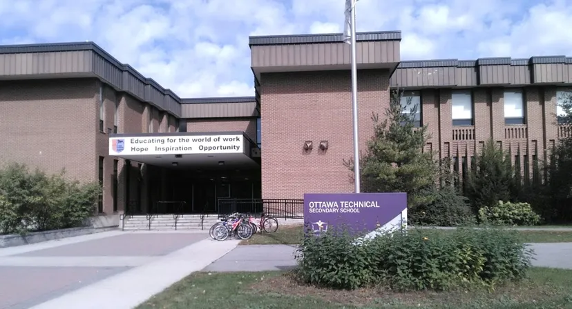 L'edificio moderno in mattoni della Ottawa Technical Secondary School con biciclette davanti all'ingresso sotto un cielo nuvoloso.
