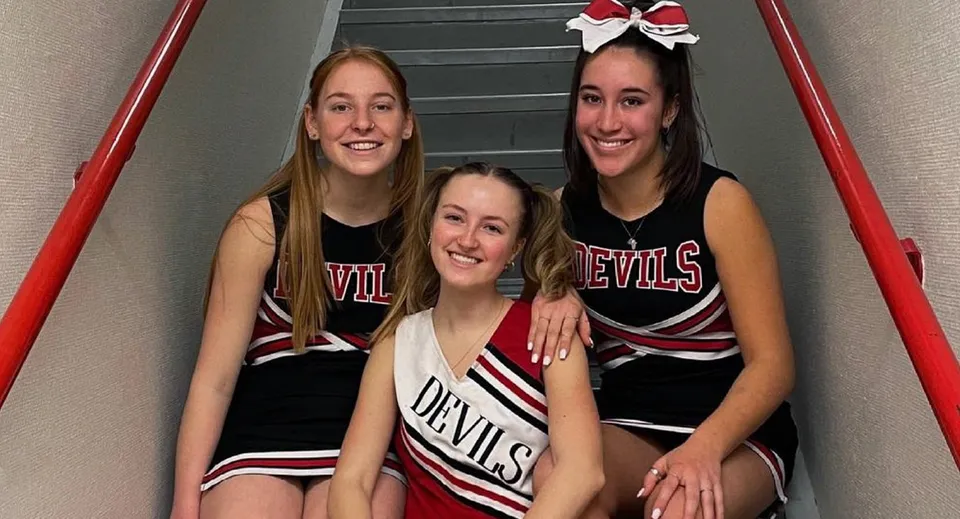 Tre studentesse della Pemberton Secondary School in divisa da cheerleader mettono in posa insieme nel vano scale.