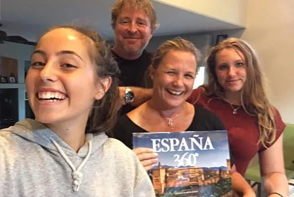 Chica sonriente haciéndose un selfie con tres personas que muestran un libro titulado España 360