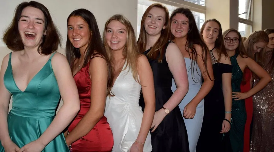 Un gruppo di giovani donne in abito formale posa insieme durante una festa al Victoria College Belfast.