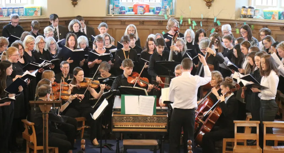 Il coro e l'orchestra della St. Peters School eseguono un brano sotto la direzione di un direttore.