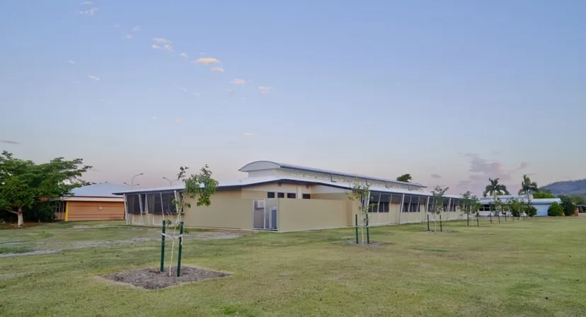 L'edificio moderno con tetto curvo all'interno del campus della William Ross State High School davanti a un campo erboso con nuovi alberi.