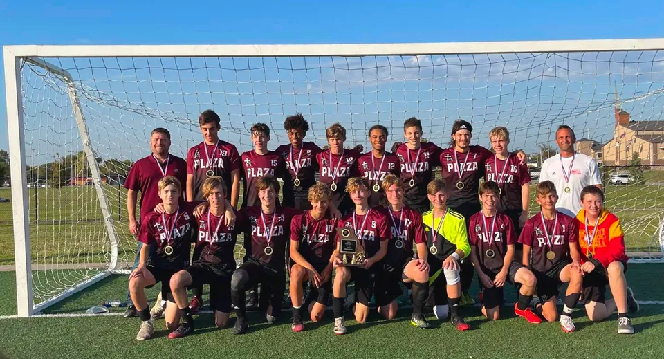 Un gruppo di studenti della Plaza Heights Christian Academy posa insieme sul campo da calcio davanti alla porta.