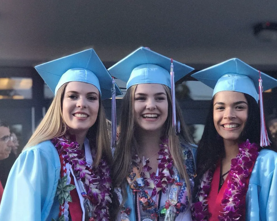 Tre studentesse della Chief Sealth High School in abiti da cerimonia posano insieme durante una festa.