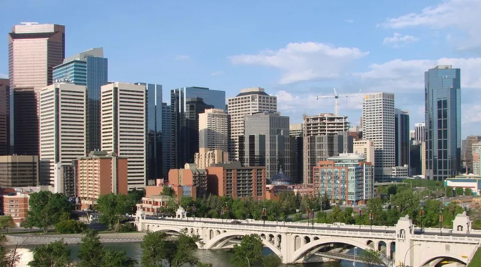 Un panorama urbano con numerosi grattacieli e un ponte ad archi su un fiume.