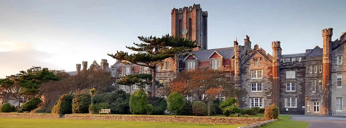 El King William's College muestra un edificio similar a un castillo con altas torres y arquitectura decorada ante un cielo despejado.