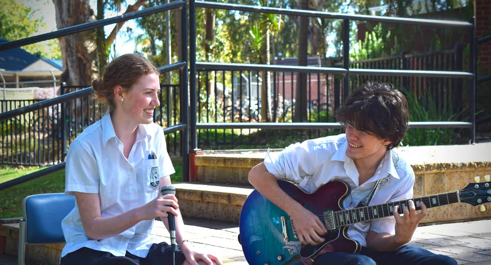 Due studenti della Marryatville High School chiacchierano mentre lo studente suona la chitarra.