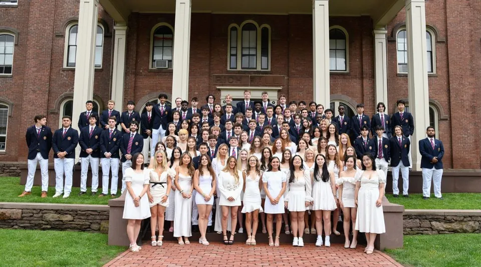 Un gruppo di studenti e studentesse in abito formale davanti allo storico edificio della Wilbraham & Monson Academy.