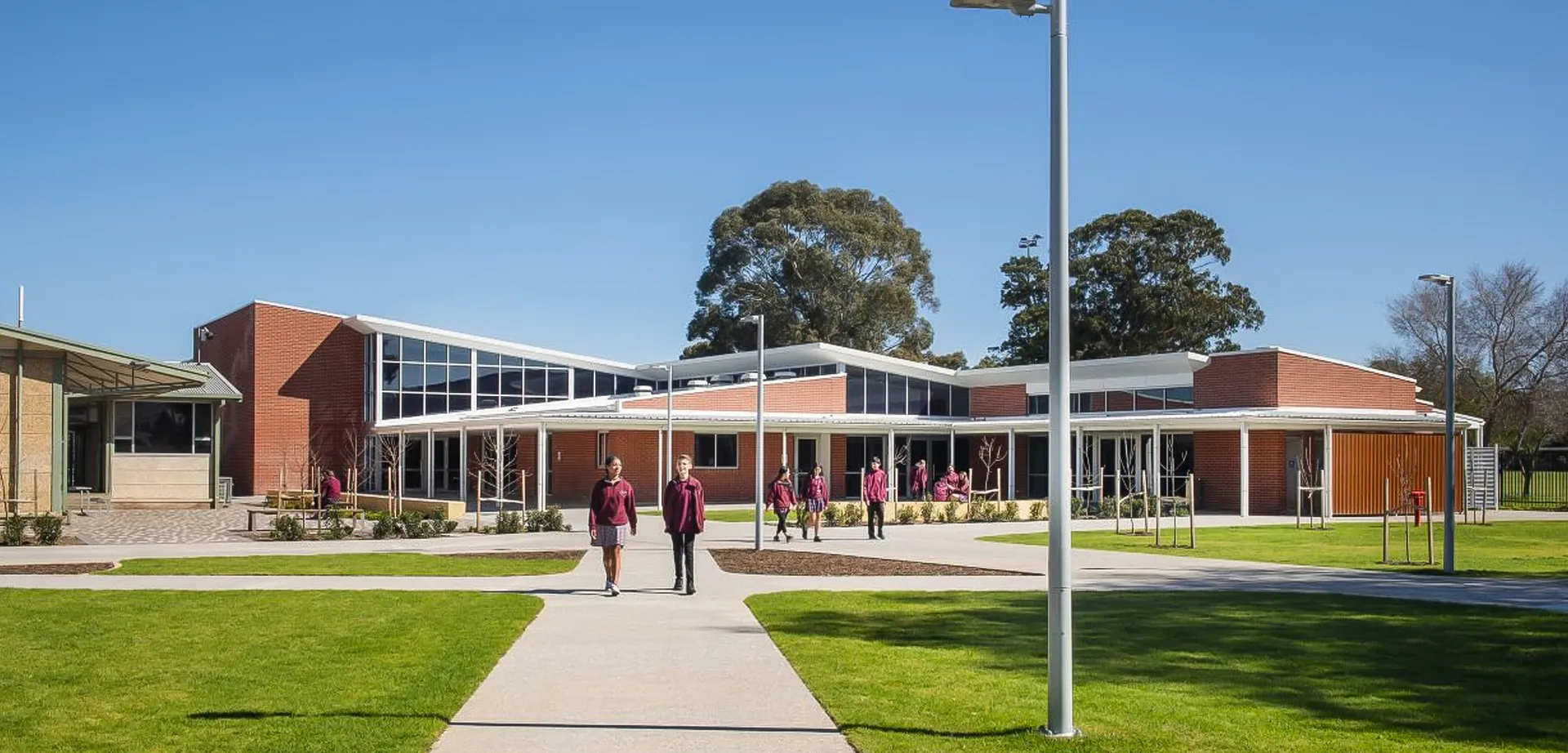 L'edificio moderno della Underdale High School è circondato da un prato e alberi, davanti all'ingresso principale diverse persone camminano su un sentiero.