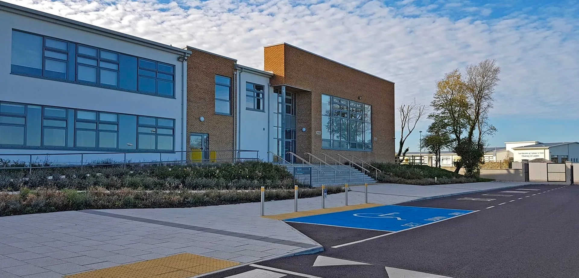 L'edificio moderno a più piani dell'Edmund Rice College con ampie finestre e un'area pavimentata blu e gialla in primo piano.