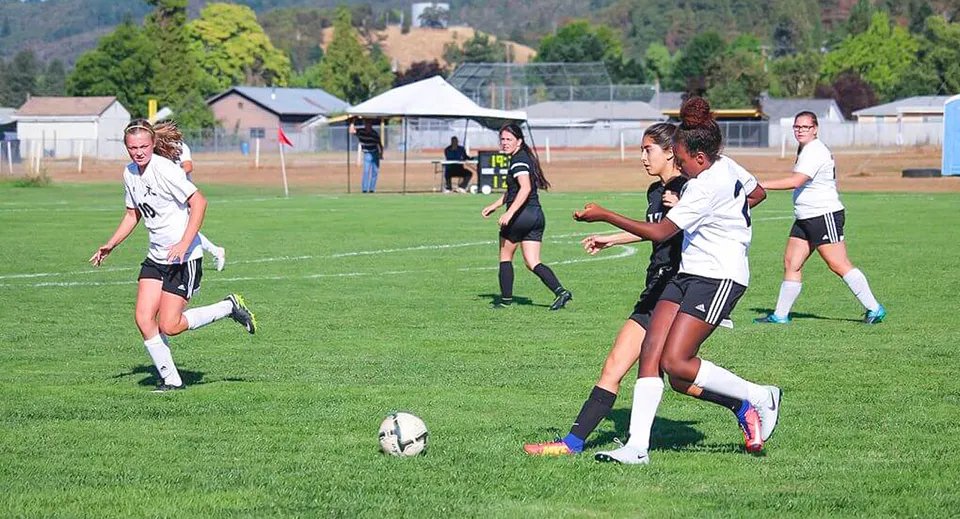 Gli studenti della Canyonville Academy giocano una partita di calcio sul campo sportivo verde.