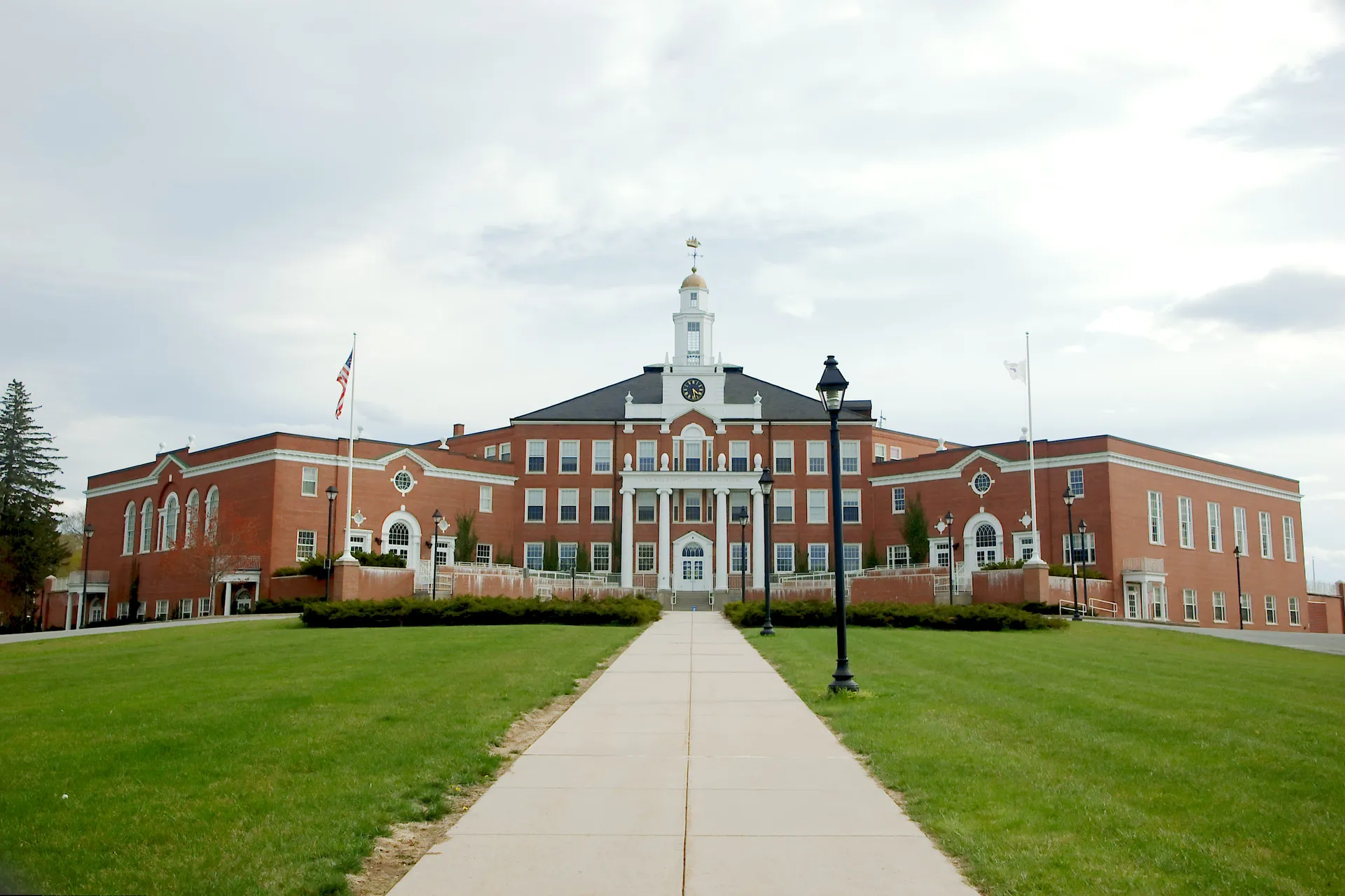 L'edificio principale della Newburyport High School con una torre centrale e un'architettura decorata su un'area verde circondata da alberi.