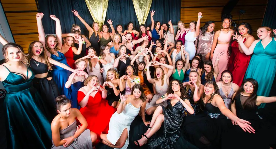 Un gruppo di studentesse del Sacred Heart College Napier in posa solenne con abiti formali e le braccia alzate.