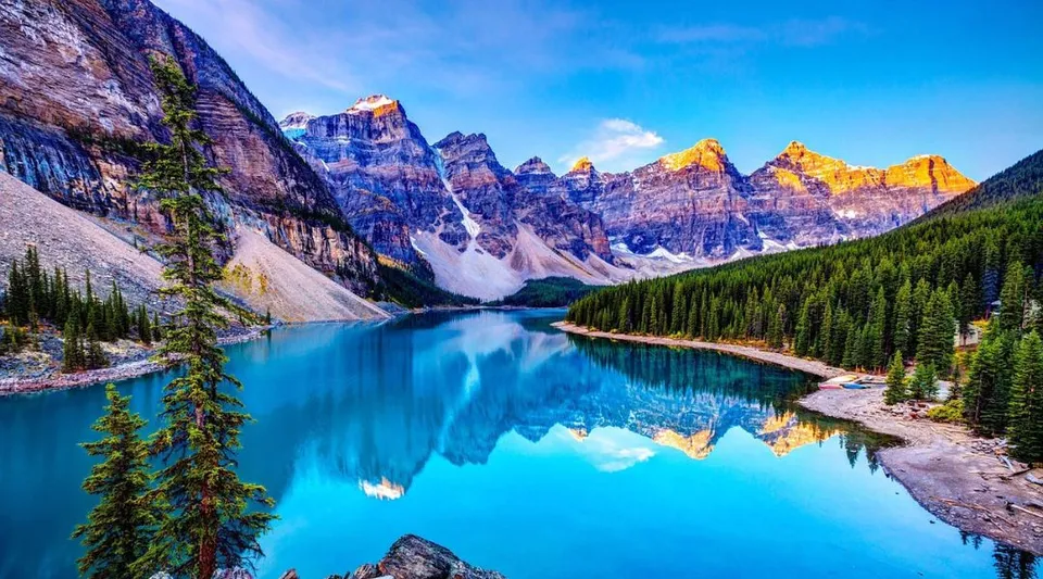 Un lago montano color turchese circondato da montagne rocciose e fitti boschi in Canada.