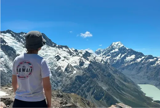 Louisa blickt von hinten auf die schneebedeckten Berge Neuseelands