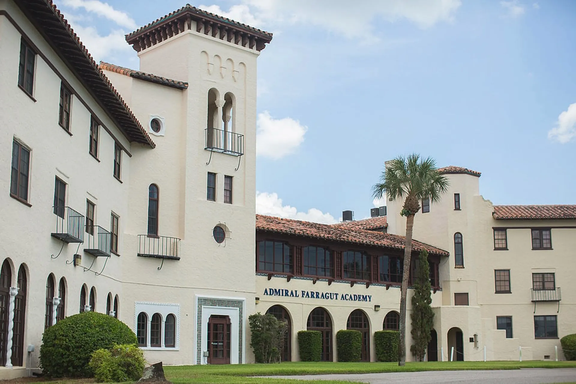 L'edificio della Admiral Farragut Academy mostra uno stile architettonico spagnolo con un'alta torre e finestre ad arco su uno sfondo di cielo blu.