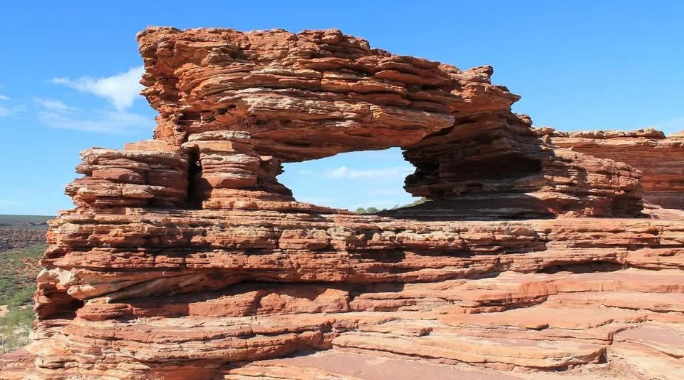 Una formazione naturale ad arco di roccia in arenaria rosso-marrone è visibile sotto un cielo limpido nei pressi della Eastern Hills Senior High School.