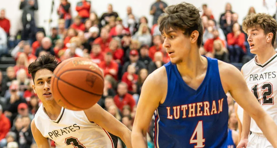 Due giocatori di basket lottano per il possesso della palla durante una partita sul campo della Wisconsin Lutheran High School.