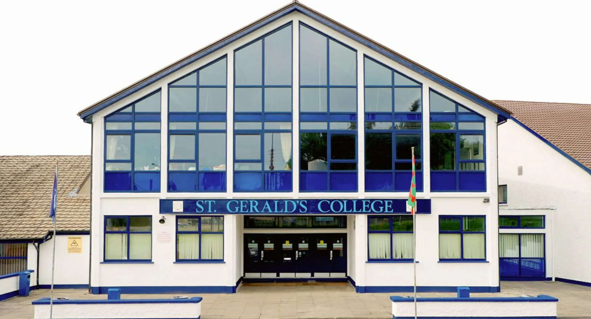 L'edificio moderno in vetro con la scritta St. Gerald's College è circondato da un'area pavimentata.