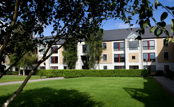 Esterno della residenza Merville dell'UCD con prato curato, siepe e alberi in primo piano