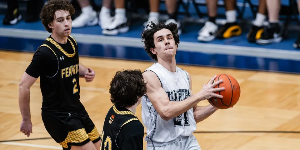 Un giocatore di pallacanestro della Bishop Fenwick High School in divisa nera difende durante una partita in palestra.