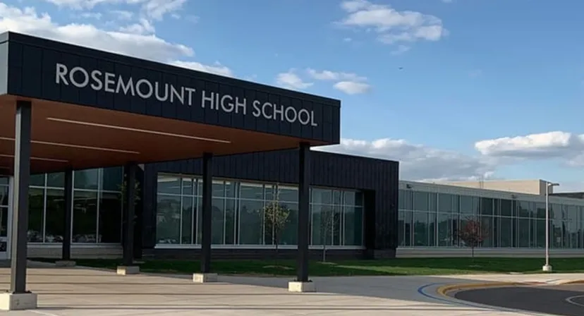 L'edificio moderno della Rosemount High School si trova davanti a un cielo azzurro limpido con nuvole.