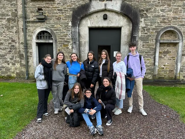 Grupo de alumnos posando ante el portón de un antiguo edificio de piedra