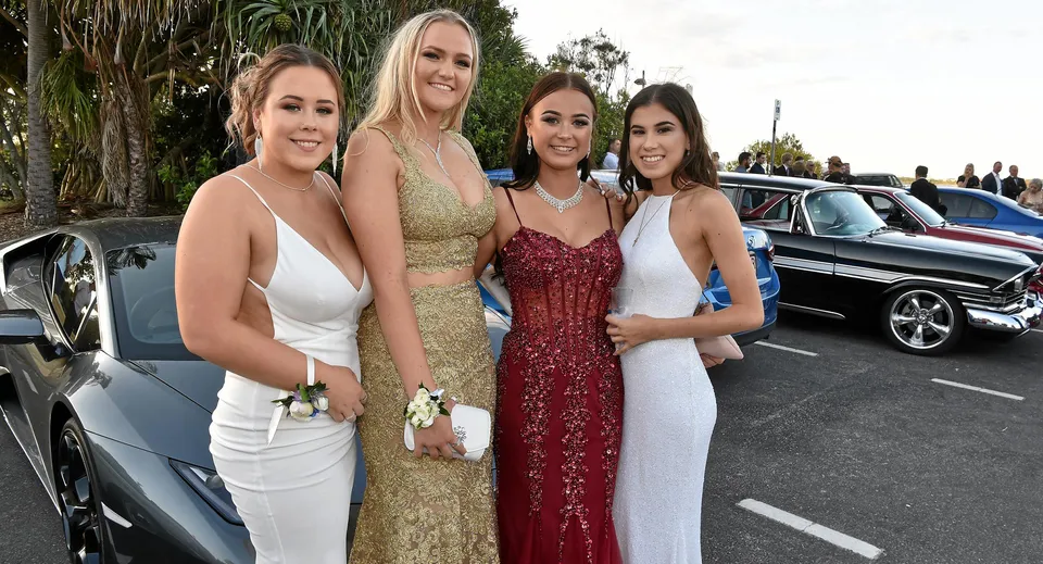 Quattro studentesse del Nambour State College posano davanti a un veicolo di lusso in un'area esterna con palme.