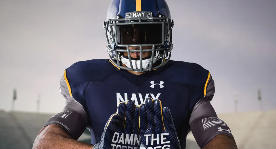 Un giocatore di football della Admiral Farragut Academy indossa una maglia Navy con la scritta "DAMN THE TORPEDOES" in un ambiente cupo.