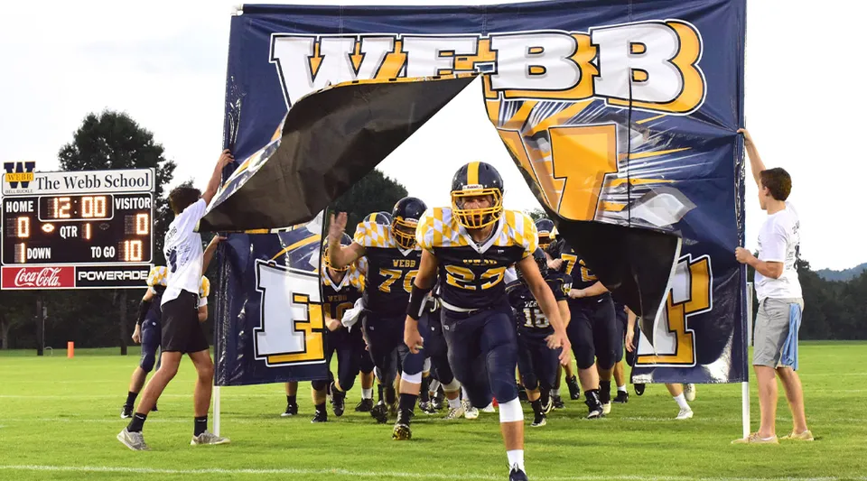 La squadra di football americano della The Webb School entra in campo attraverso un grande striscione.