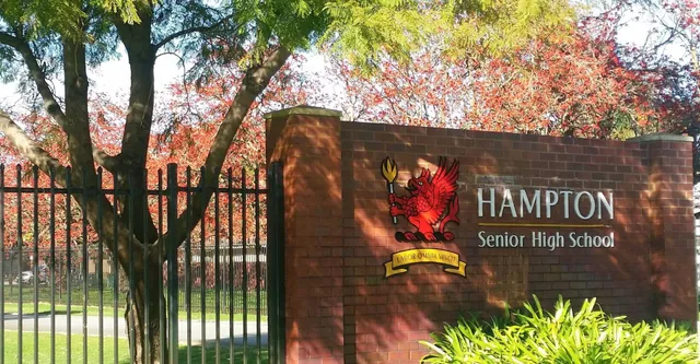 Das Ziegelschild von Hampton Senior High School steht vor bunten Bäumen.