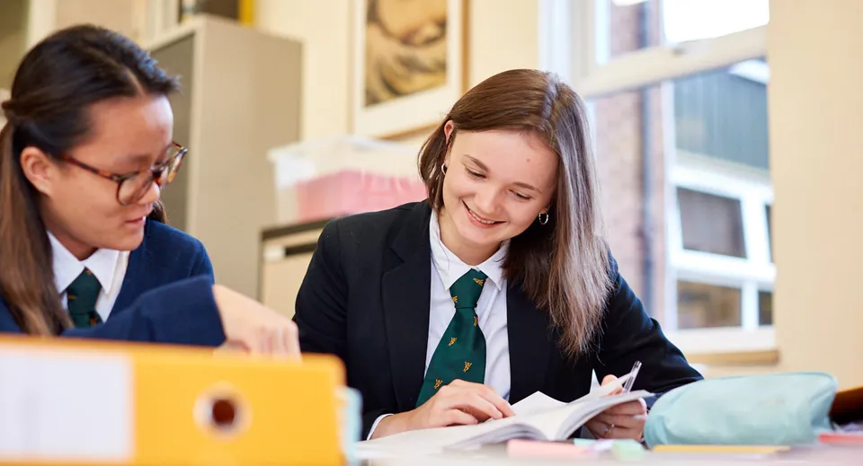 Due studenti in divisa scolastica lavorano insieme a un compito al tavolo nel campus del Christ College.