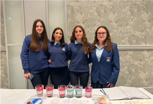 Vier Schülerinnen in Uniform hinter einem Stand mit selbst gemachten Kerzen in Irland