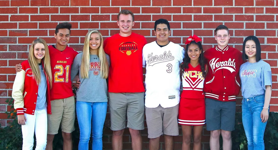 Un gruppo di studenti della Whittier Christian High School è davanti a una parete di mattoni rossi con diverse maglie sportive e abiti casual.