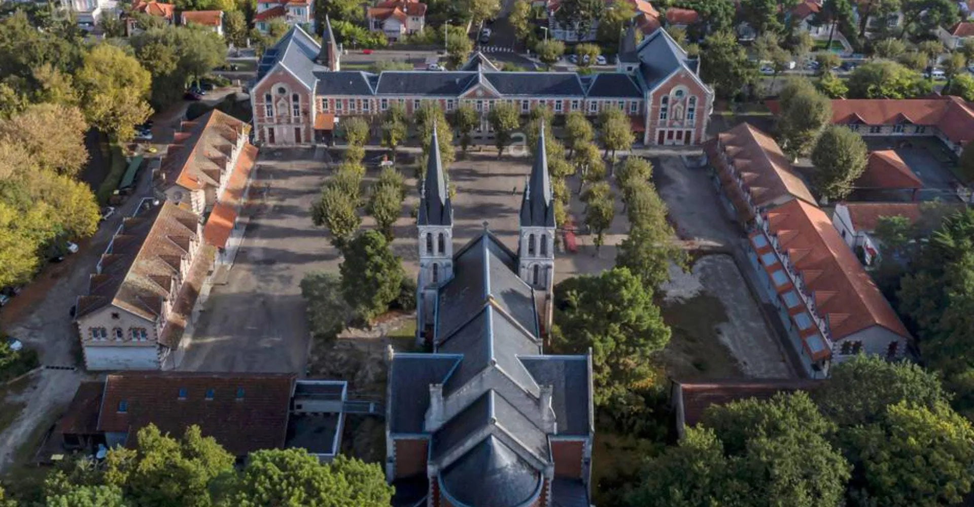 La cattedrale storica nel campus del Lycée St Elme è circondata da alberi verdi e altri edifici.